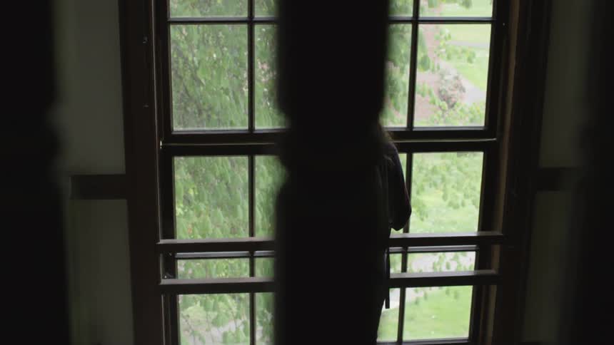 Woman wearing a backpack looking through a window