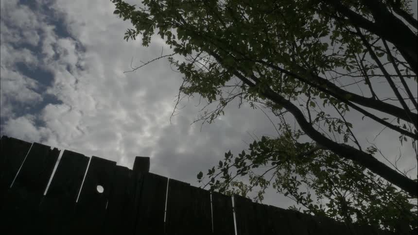 Time lapse of clouds passing by atop a wooden fence