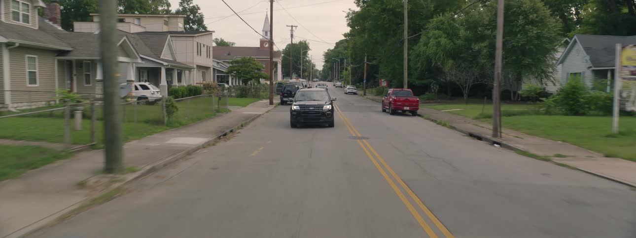 Car drives through suburban neighborhood in the daytime