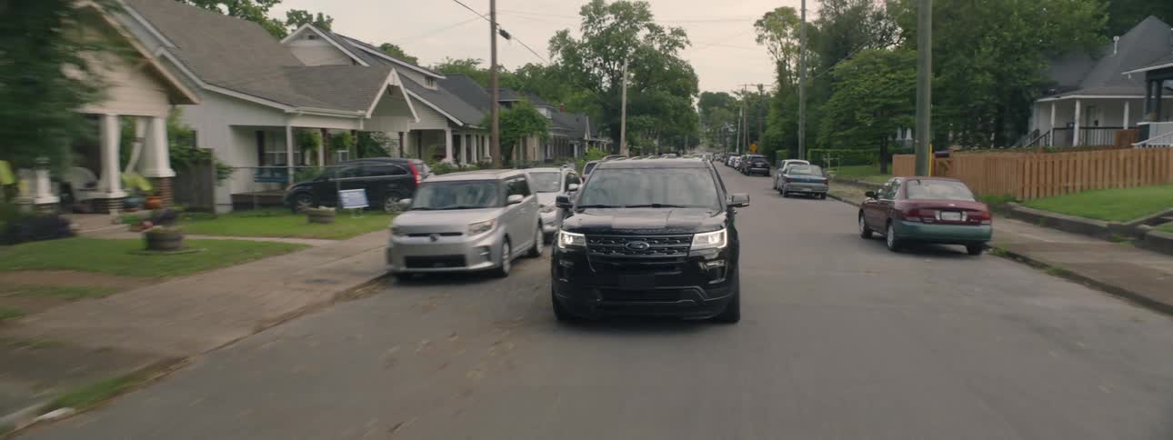 Car drives down road towards camera while camera tracks