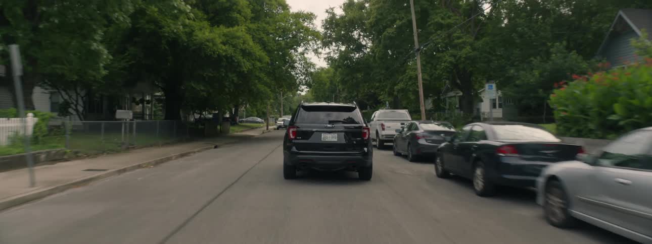 Car drives down street away from camera as camera tracks it