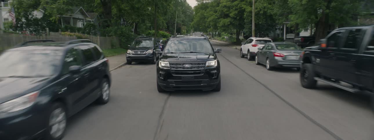 A black suv drives fast down a city street
