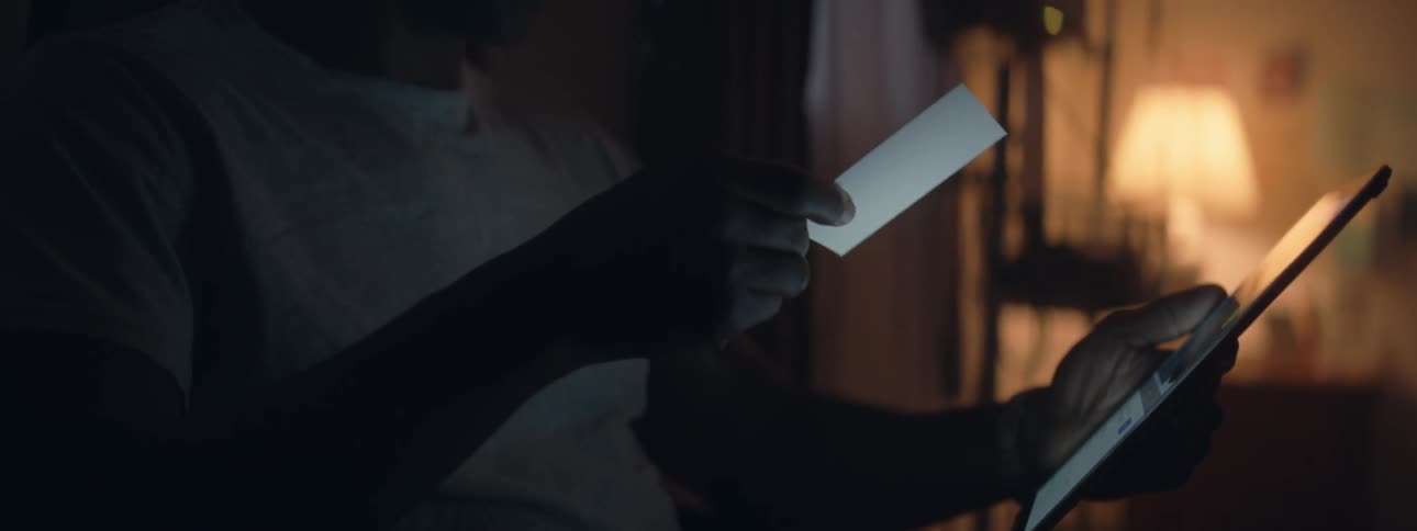 Person taps on a tablet then looks at a piece of paper