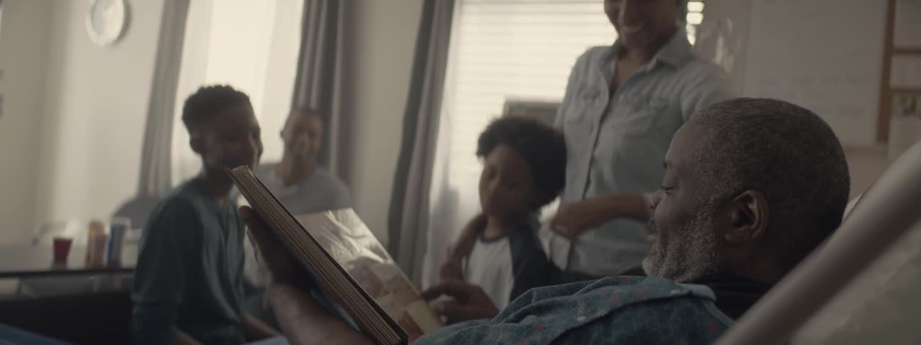 A man in a hospital bed looking through a photo album