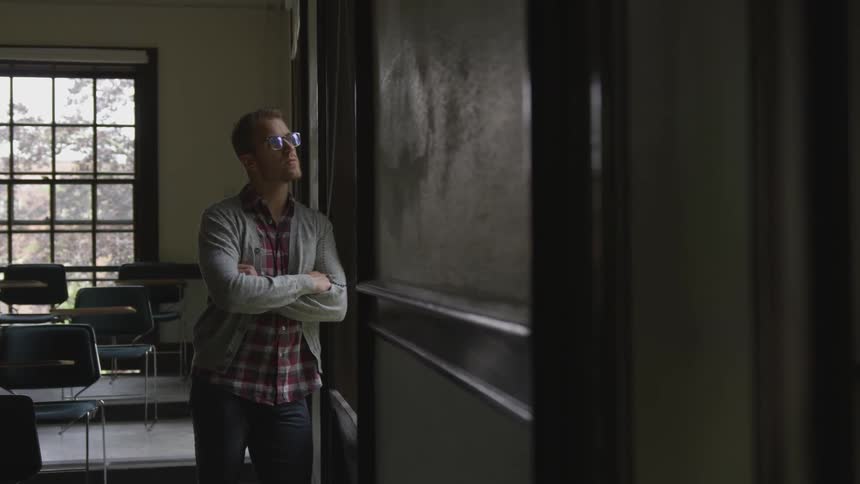 Man leaning on a wall looking out a window
