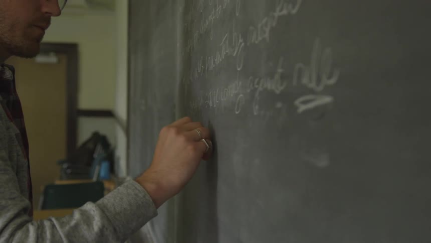 Man at a classroom writing on a blackboard