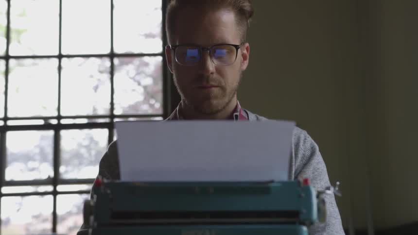 Man sits and operates a typewriter