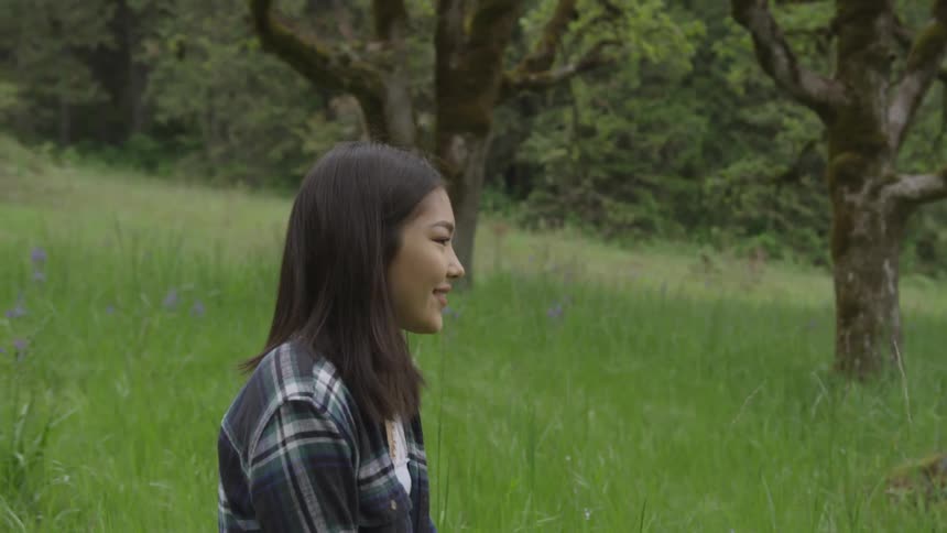 A woman smiling standing by the trees