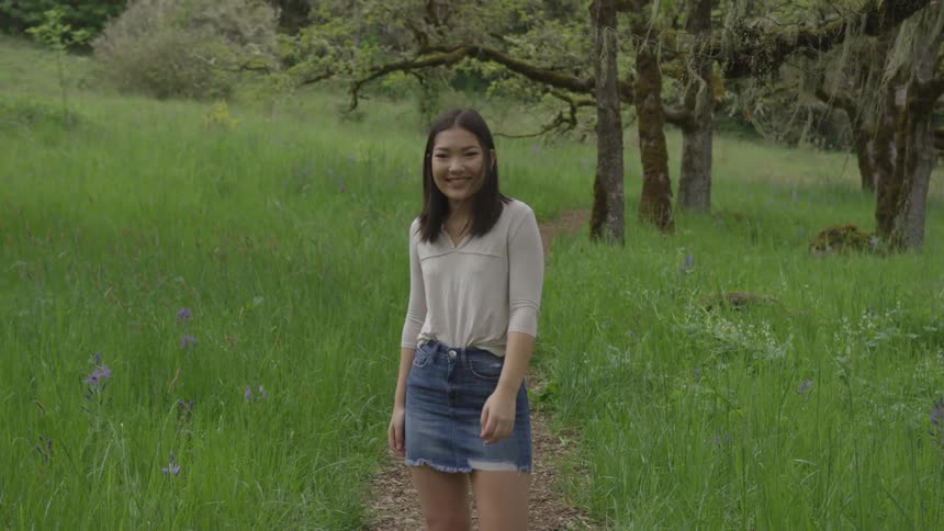 Woman wearing mini skirt poses for photographs on forest path during the day