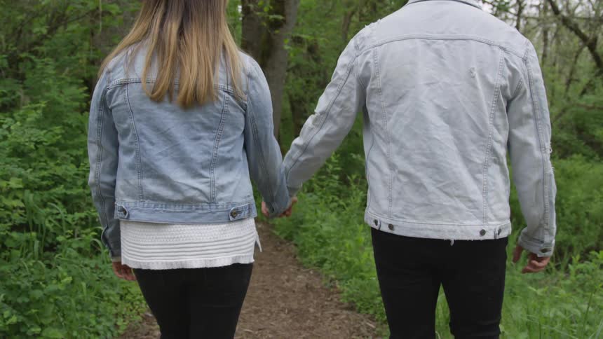A couple walks down a path holding hands