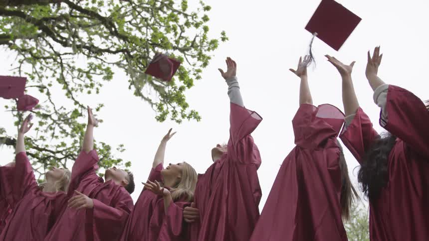 Graduates throw graduation caps into the air
