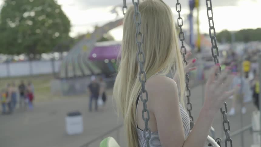 Woman sits on swing during day at fair ground