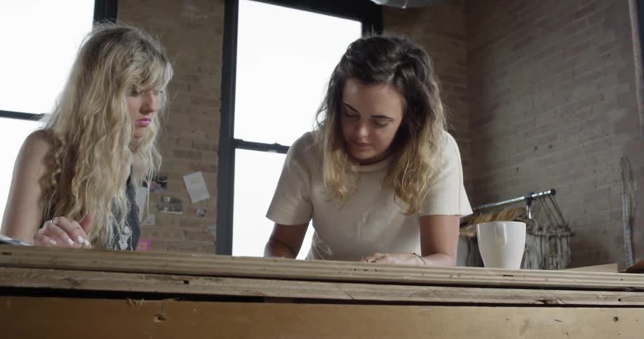 Two women working on something at a wooden table