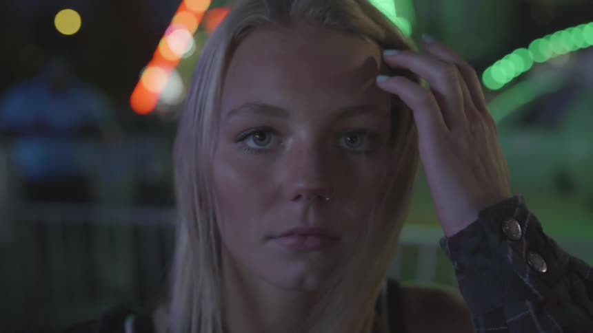 Blonde girl who has green eyes lifts head looks at camera at night