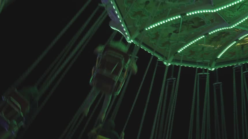 People riding a fair swing fly overhead