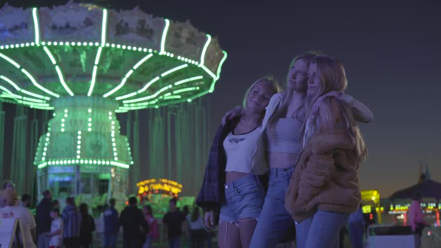 Three teenage girls at a carnival at night