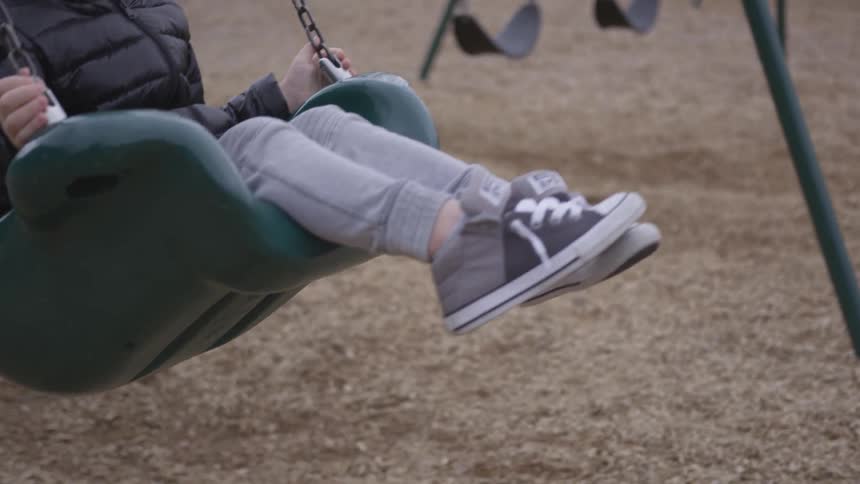 Two children ride on playground swings