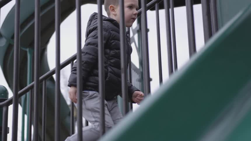 A child runs up the stairs on playground equipment