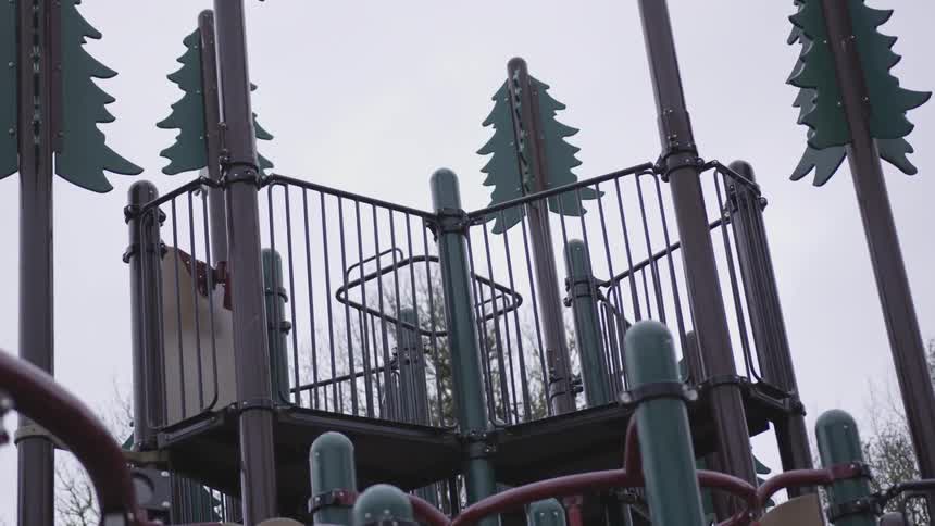 A playground in a park with tree decorations on the poles