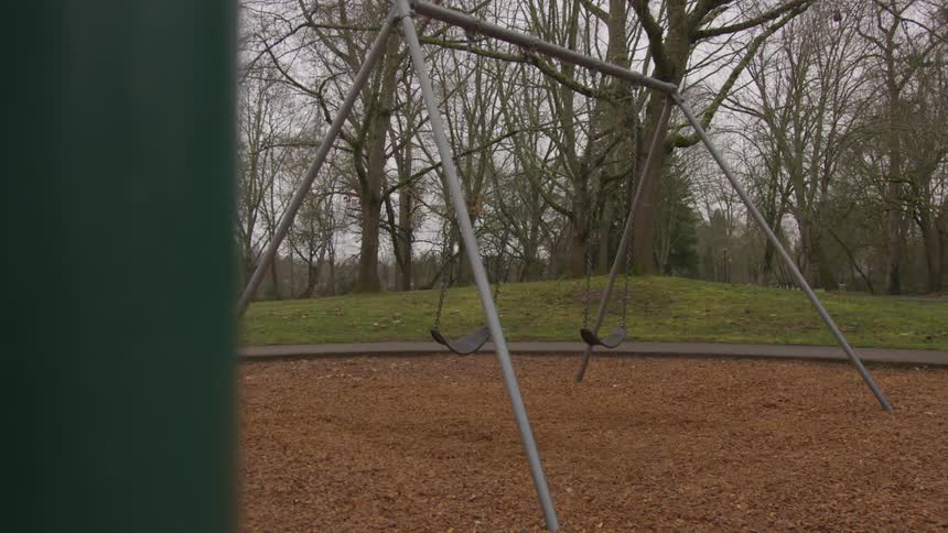 Swings swing in the air on a cloudy day in the playground