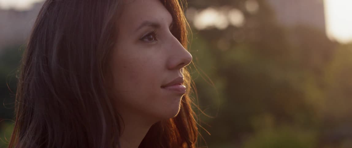 A woman standing in a field looking up on a sunny day