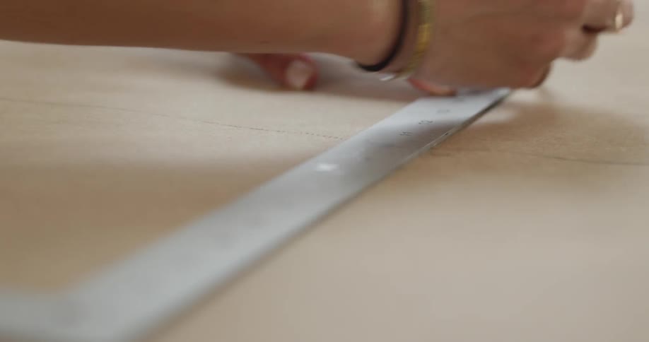 Woman uses yardstick and pencil to make a line