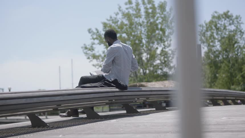 A young man sets his jacket on a bench and sits down