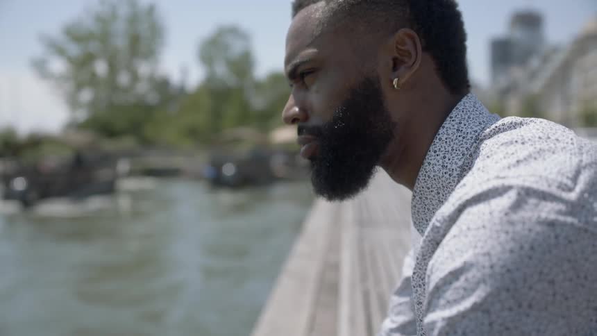 Man takes earbuds out of ears while standing near water