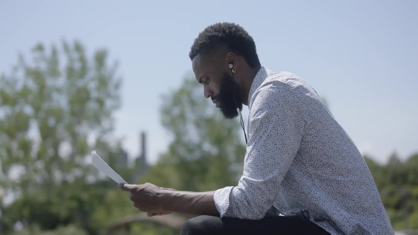Man sitting on bench in pack reading papers