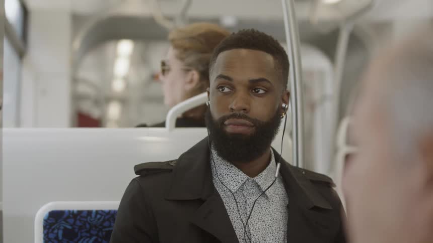 Man sits on train looking out window