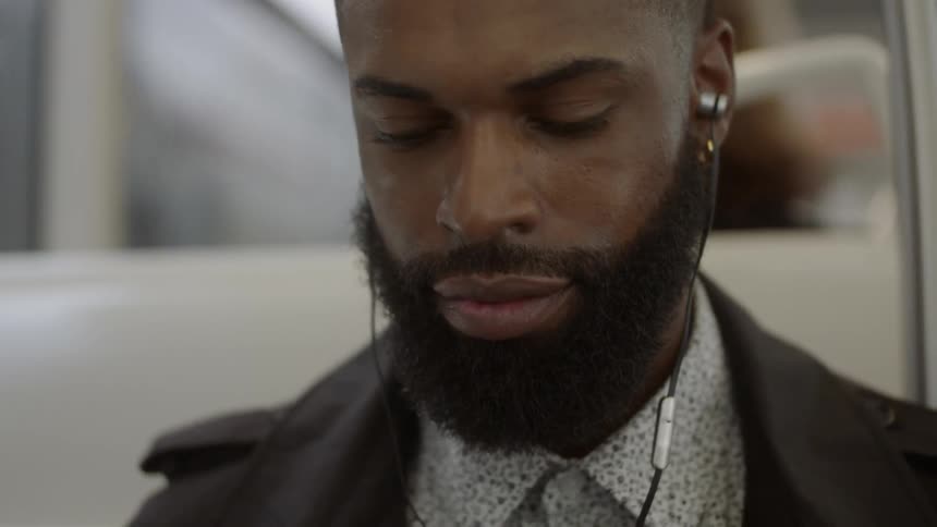 A man with earbuds on public transportation