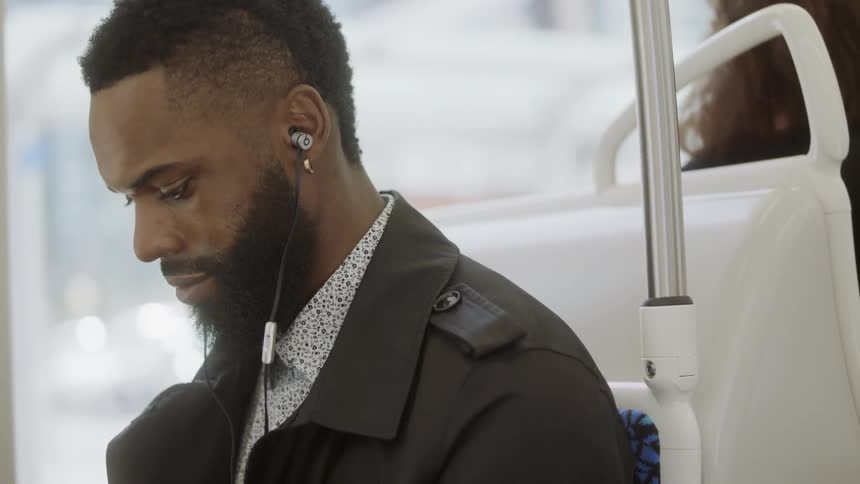 Man riding on bus with earbuds