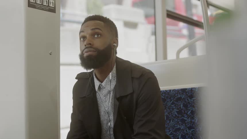A man in a carriage sits down with earphones in his ears