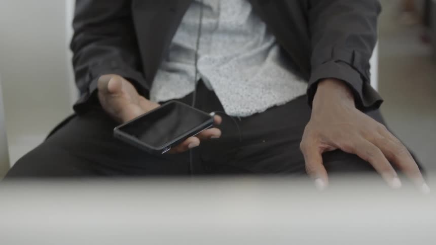 Man holds his cell phone as he sits