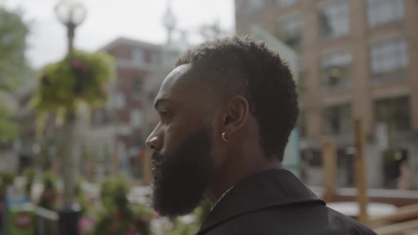 Man wearing earrings walks down the street in the city during the day
