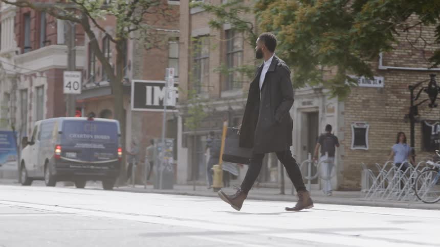 A man walking across the street with a bag