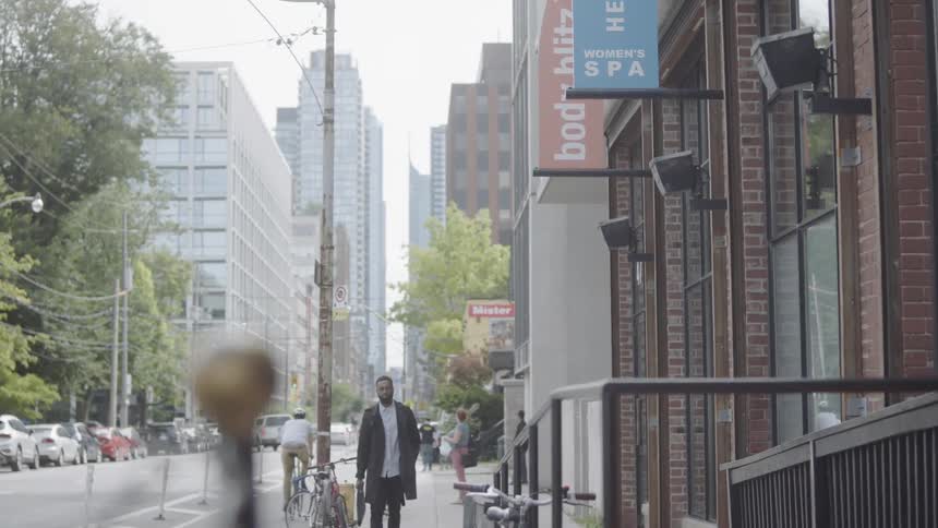 Man walking downtown carrying a briefcase as a man on bike rides by