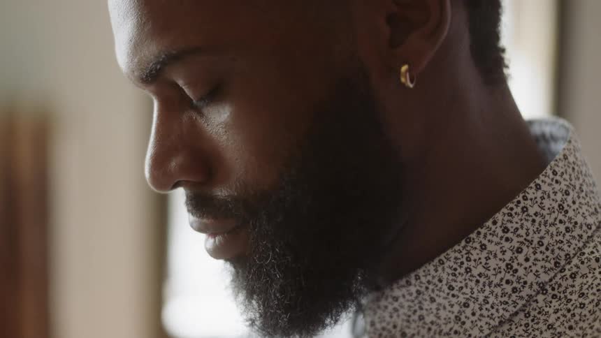 Man who has earrings and shirt on read book a table by day