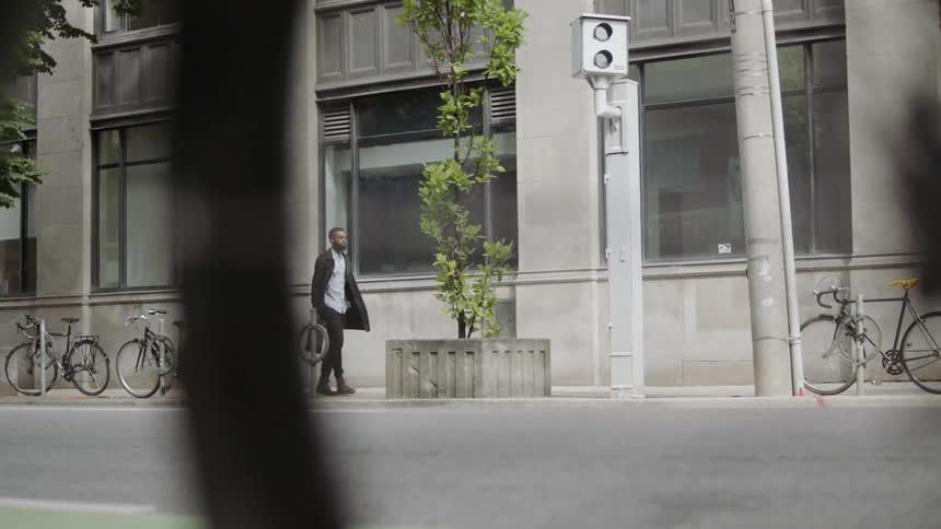 A man walks down the sidewalk by a road in the city