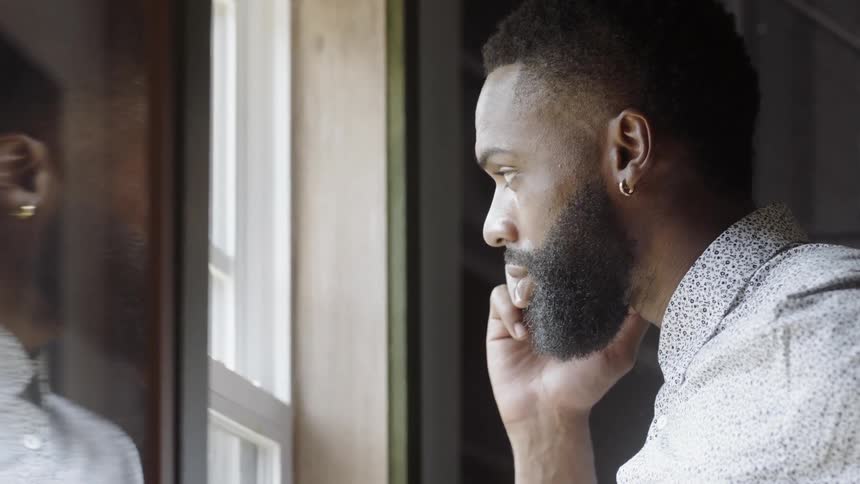 A man looks out the window while talking on the phone