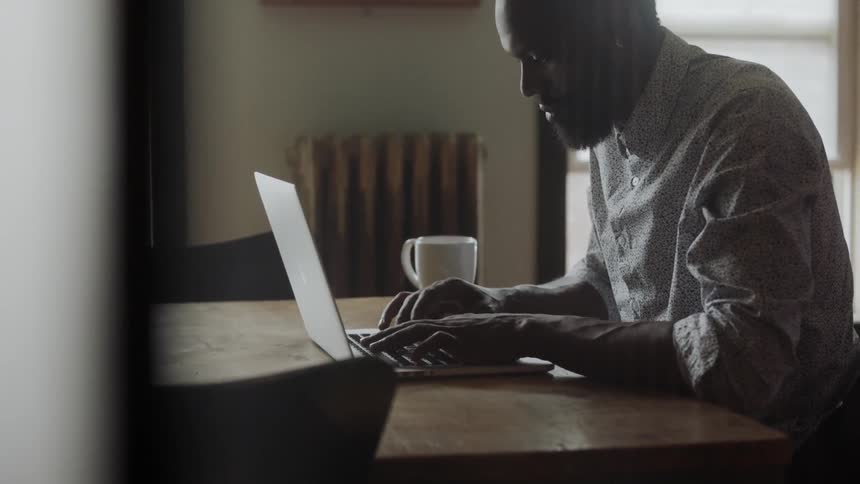 Man sitting at a desk and typing on his laptop