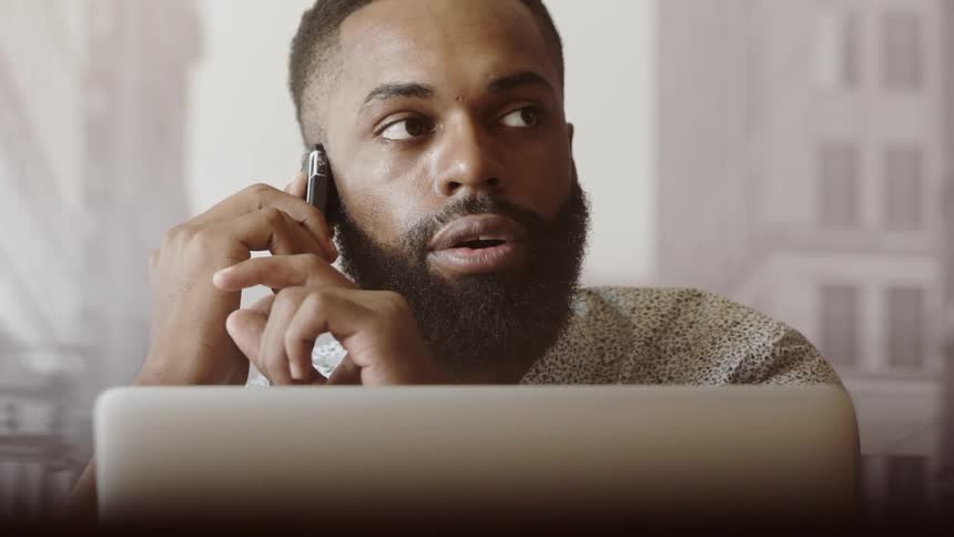 A black man is talking on the phone