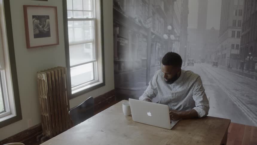 Black man sitting at a desk on a computer
