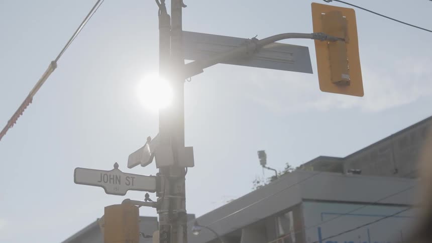 Sun shines behind traffic lights pole during the day