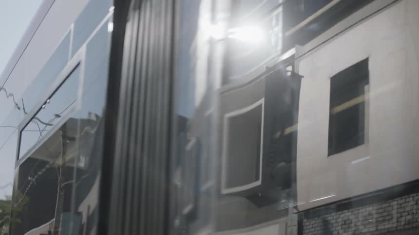 Buildings reflecting off of a city bus passing by