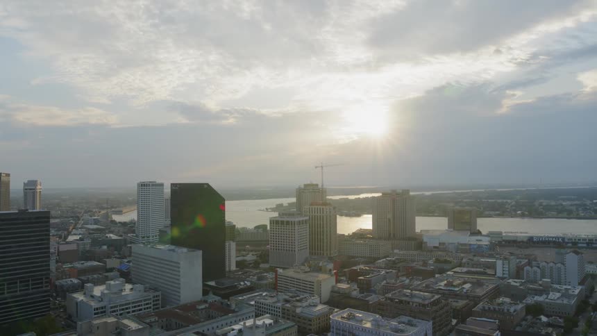 The sun shines over city buildings and skyscrapers on a cloudy day