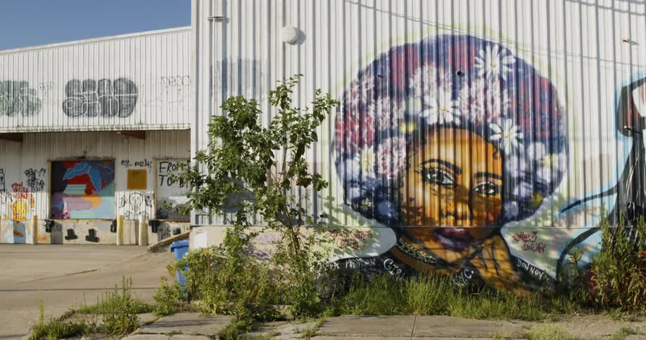 A graffiti portrait of a woman painted on the siding of a building seems to look around in thought