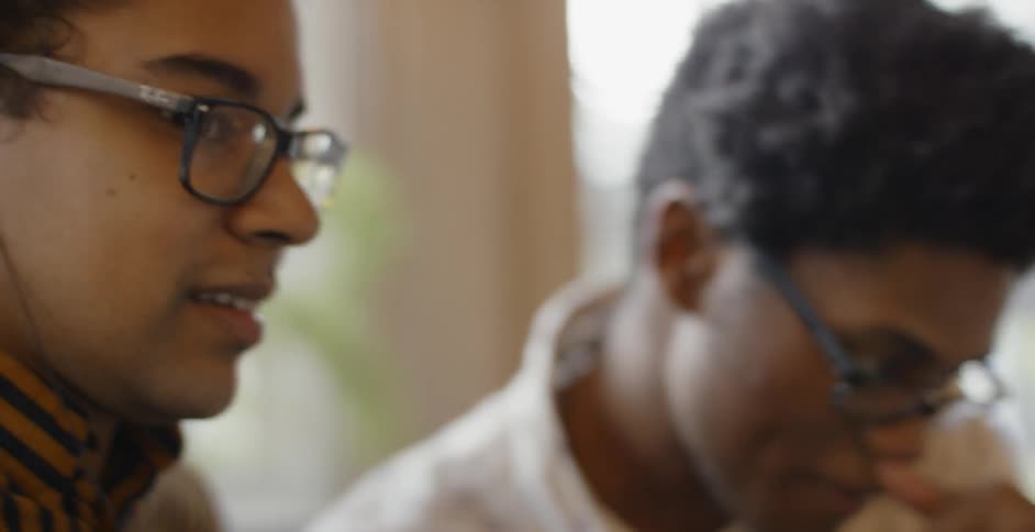 Two young men talking and working on something together