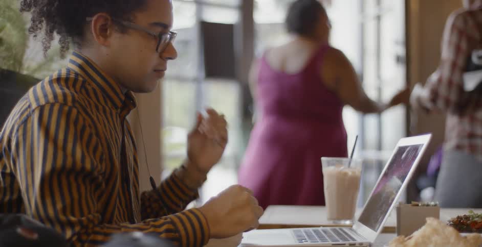 A man is putting headphones in at a coffee shop