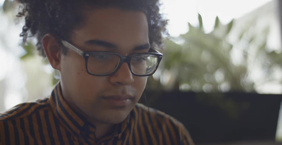 A young black man is nodding his head as he is concentrating on the task in front of him